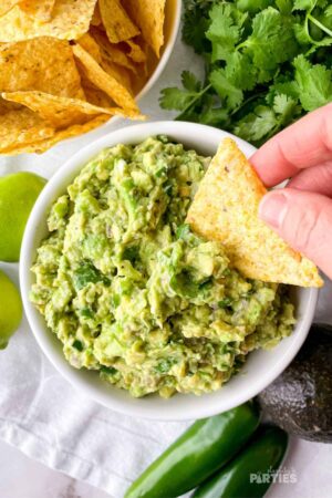 A tortilla chip being dipped into guacamole.