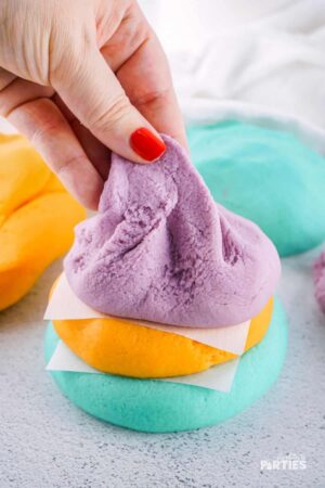 A woman's hand pulling at a finished recipe for homemade playdough.