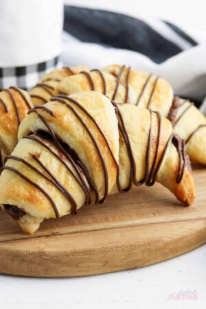 Close up of a crescent roll filled with Nutella and drizzled with chocolate.