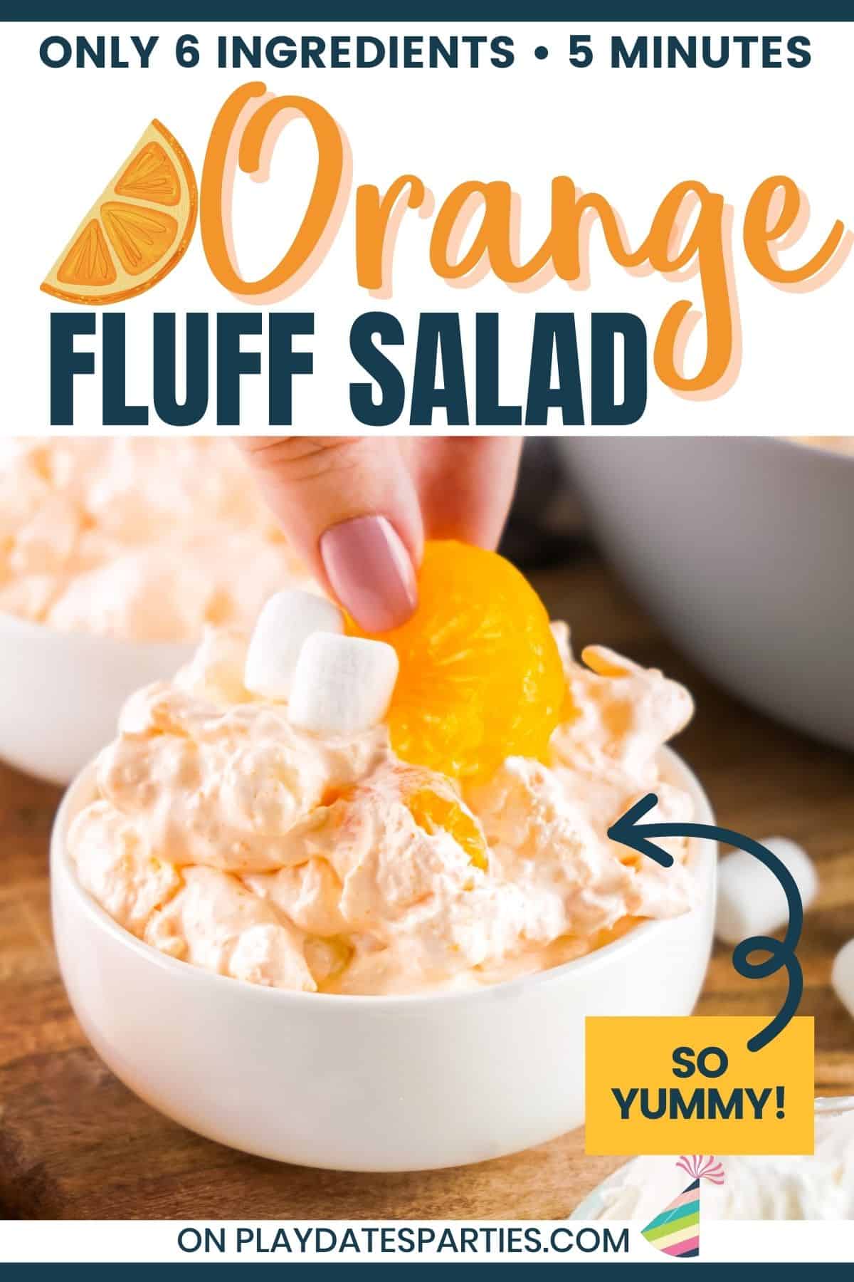 Orange fluff salad in a single serving bowl being garnished with extra mandarins and mini marshmallows.