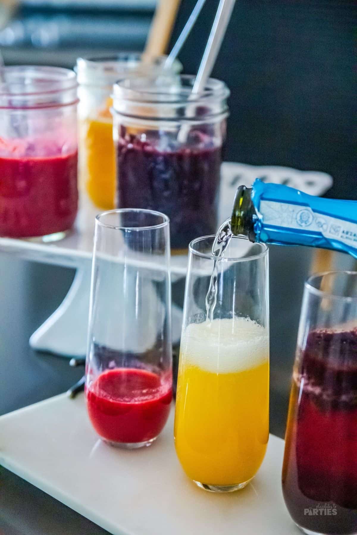 Pouring champagne into flutes with fruit puree.