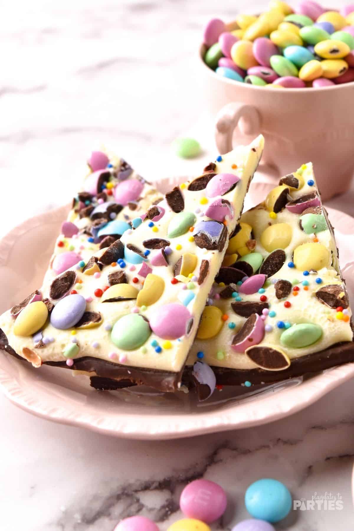 Three slices of Easter bark with M&Ms on a Pink Plate.