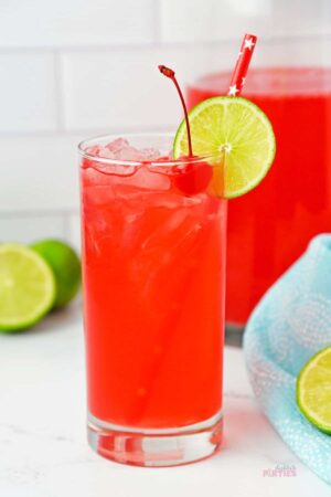 A glass of cherry limeade on a white counter.