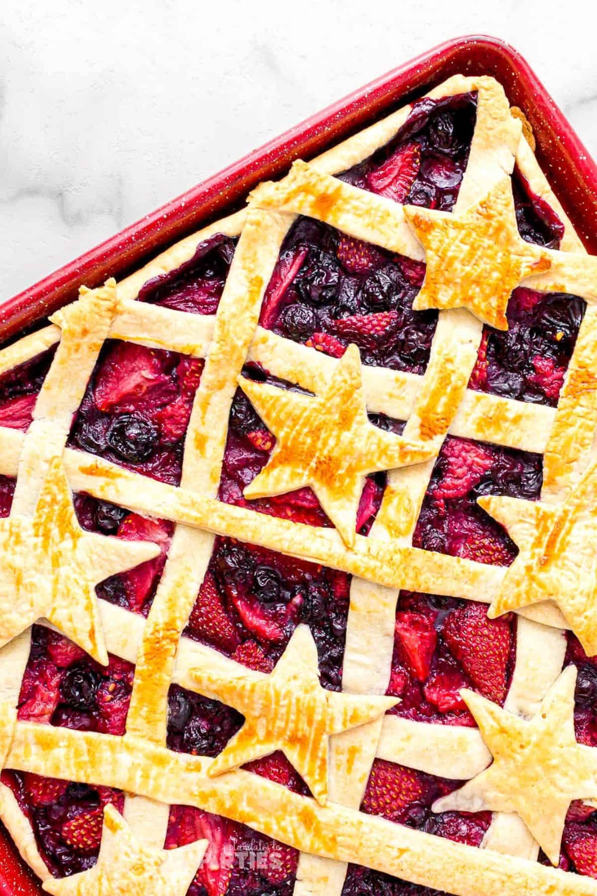 A red sheet pan with mixed berry filling and patriotic pie crust topping.