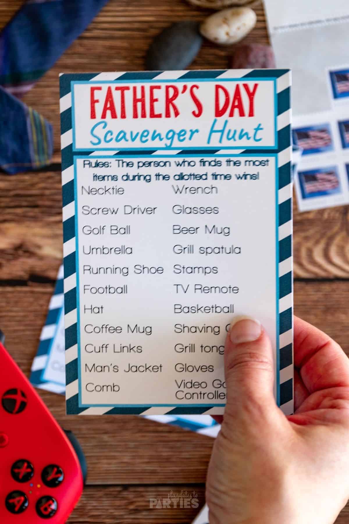 A woman's hand holding a Father's Day Scavenger hunt card.