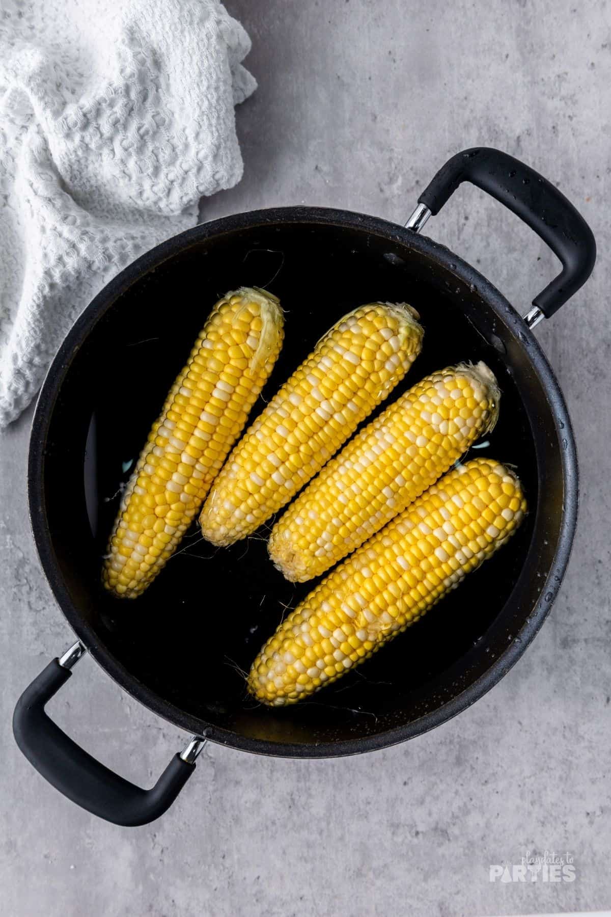 Four Ears of corn in a large pot of water.