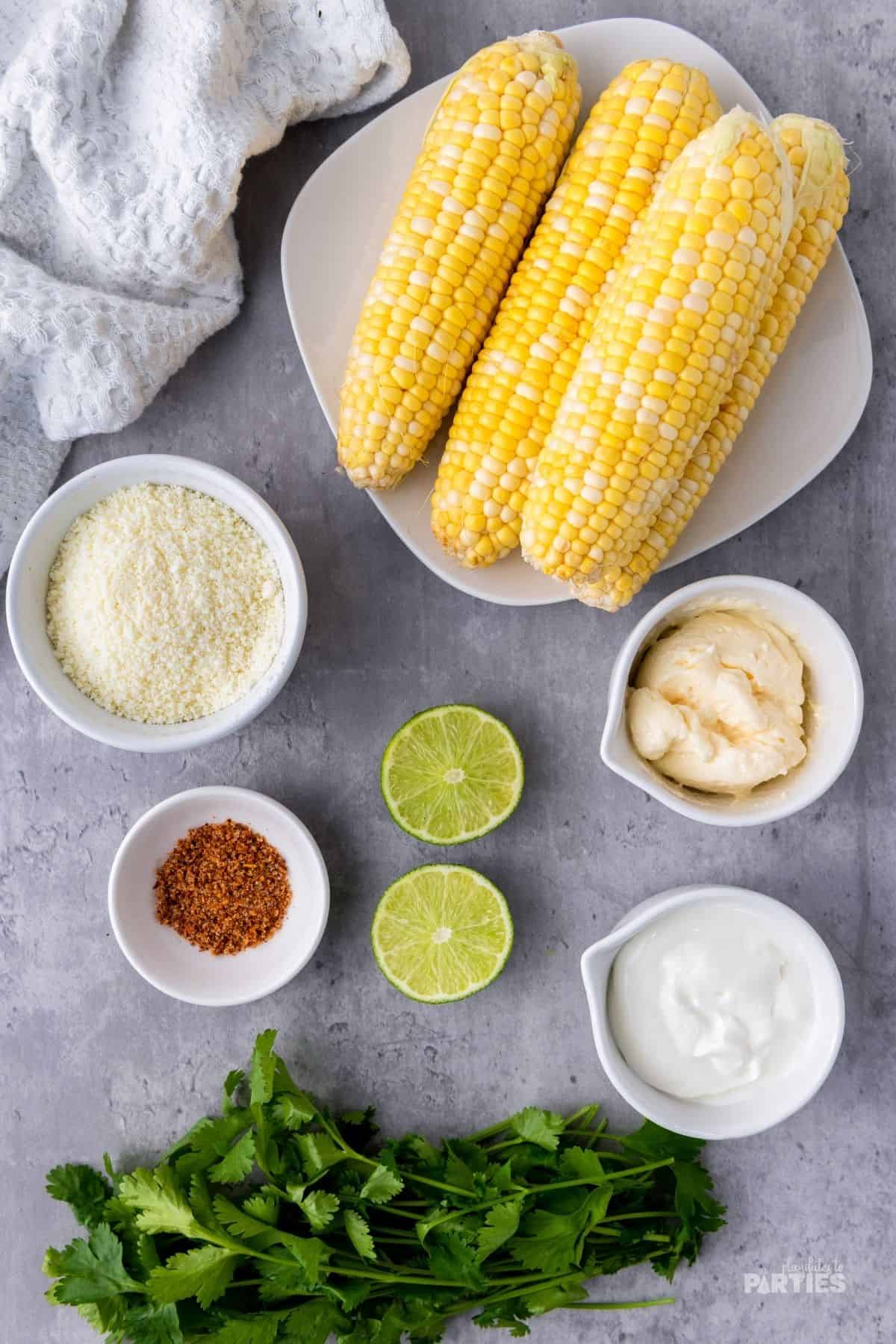 Ingredients for Elotes recipe include corn, Cotija cheese, mexican crema, mayonnaise, Tajin, limes, and cilantro.