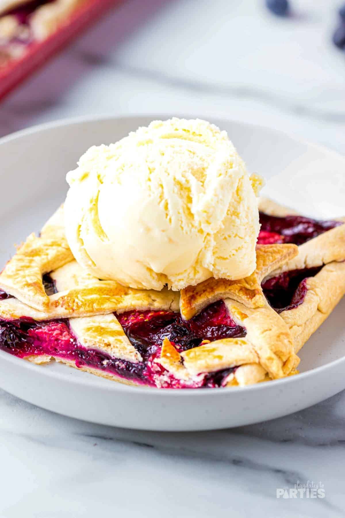 Strawberry, raspberry, blueberry pie with a scoop of vanilla ice cream.