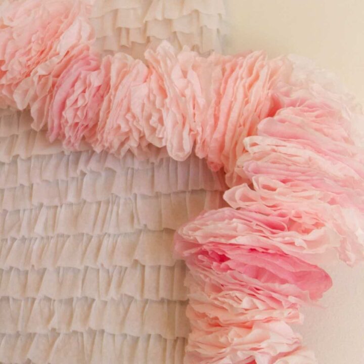 A fluffy pink garland draped along a white ruffle backdrop.