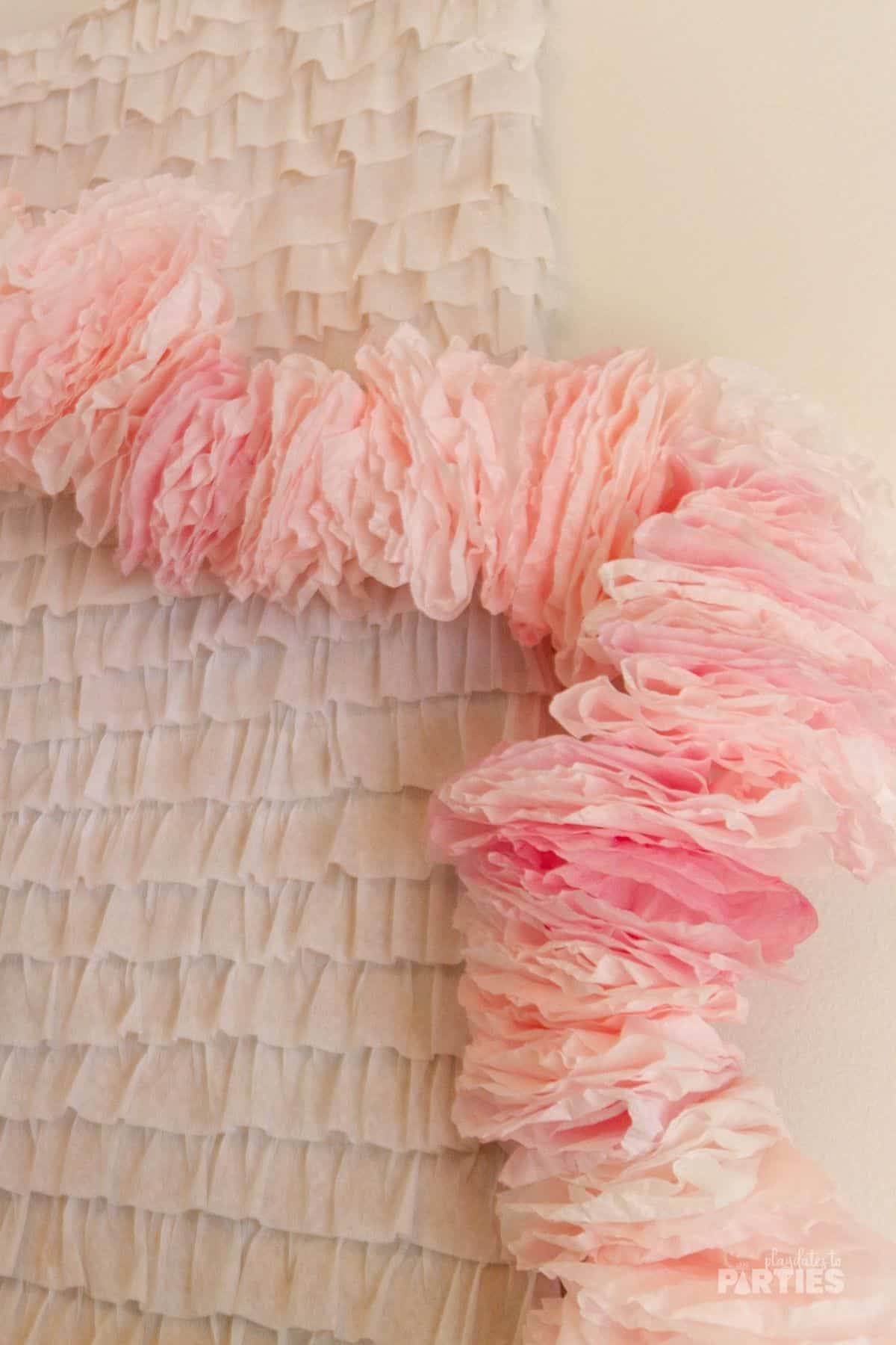 A fluffy pink garland draped along a white ruffle backdrop.