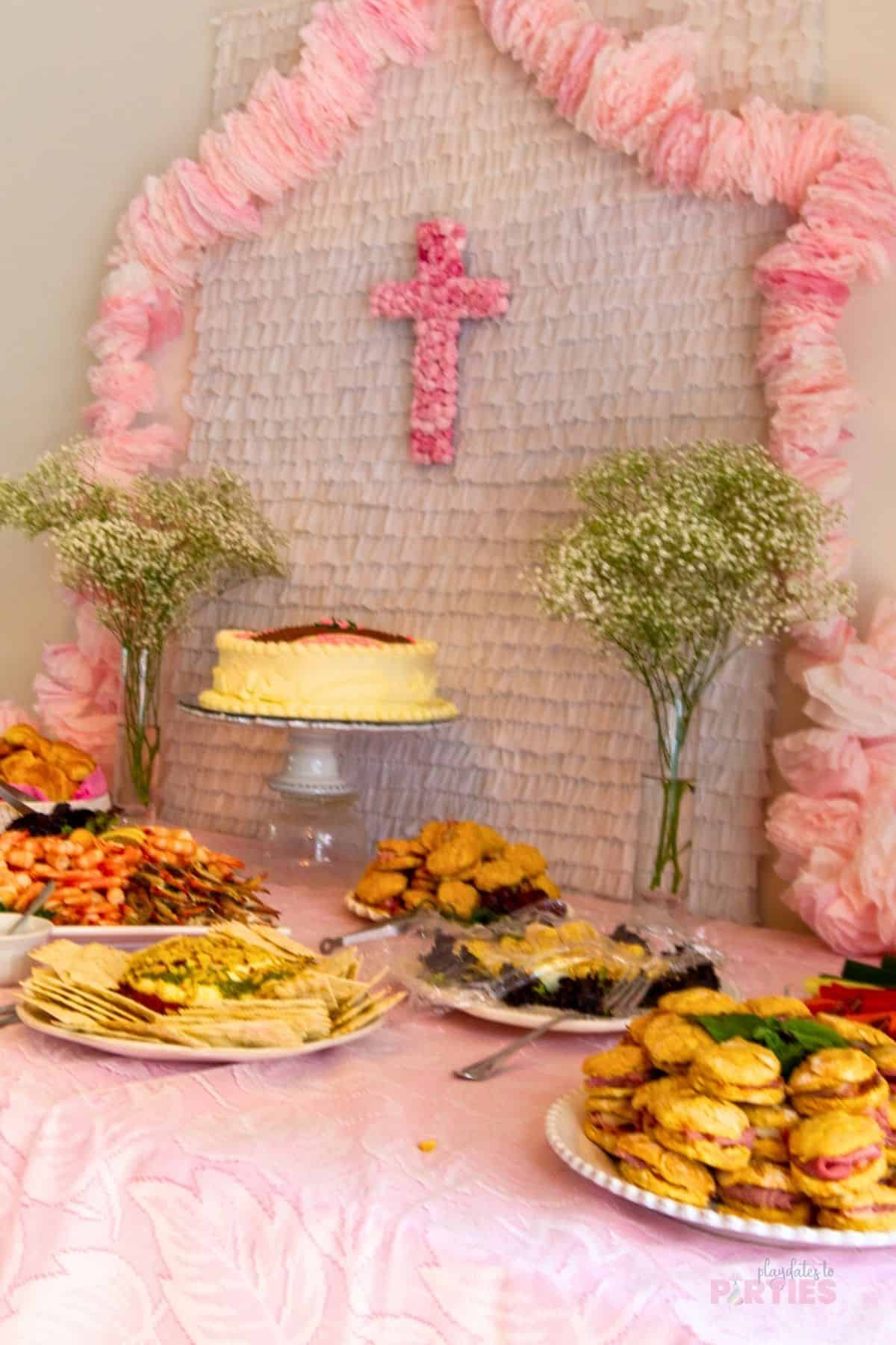 A girls pink baptism with a lace tablecloth pink coffee filter garland, and pink rose cross.