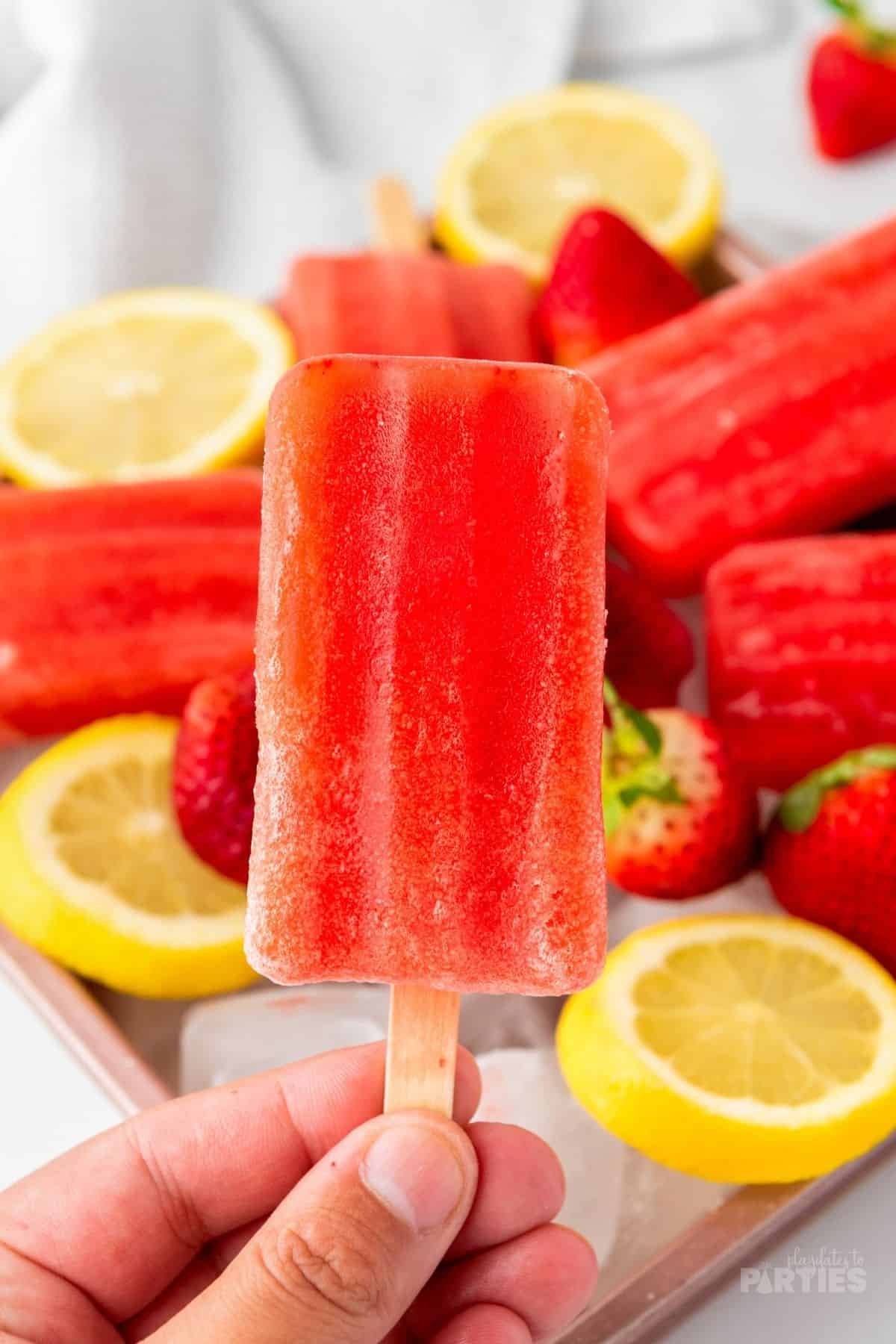 A woman's hand holds a red homemade popsicle.