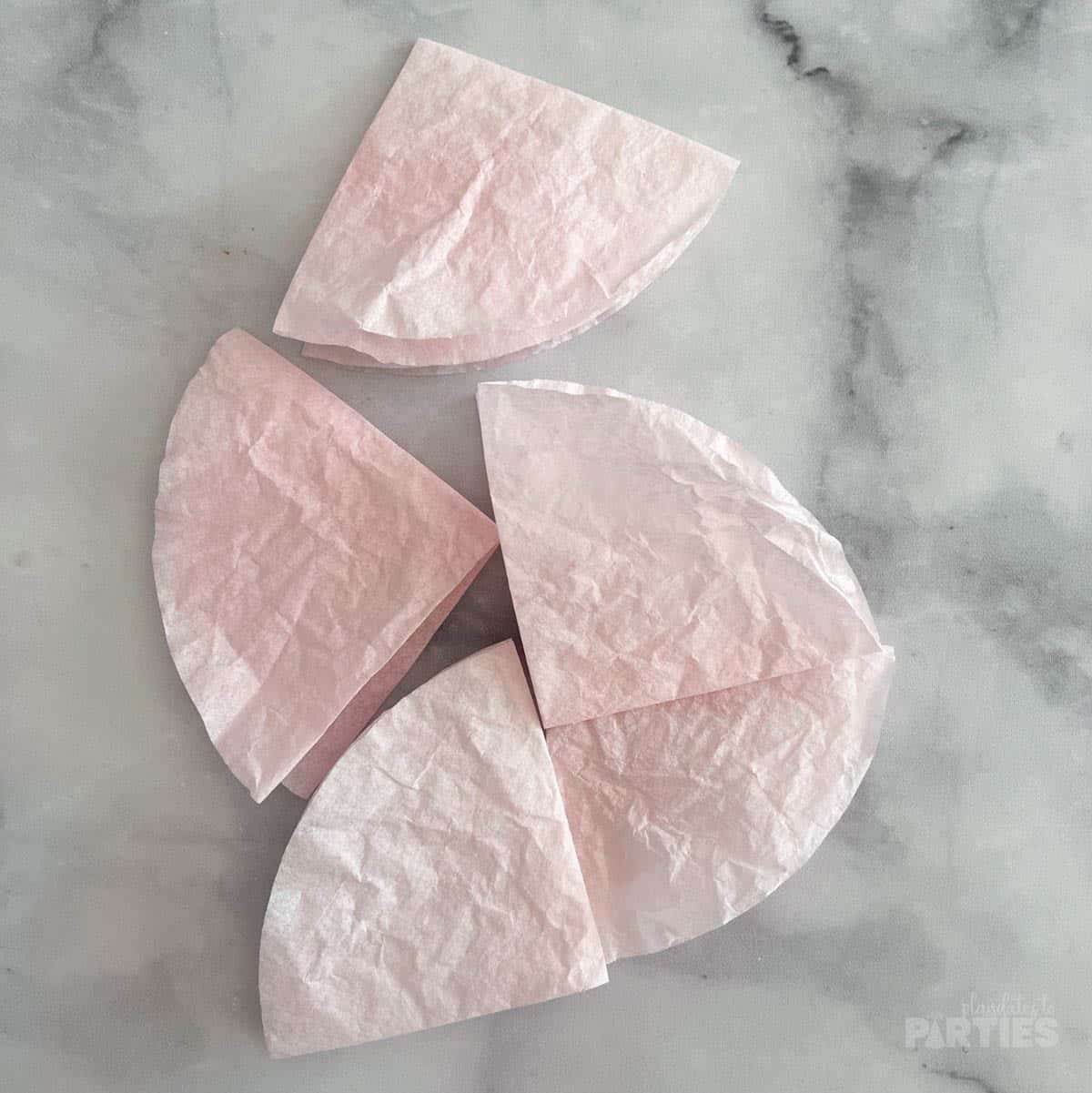 Coffee filters folded into quarters and strewn on a marble surface.