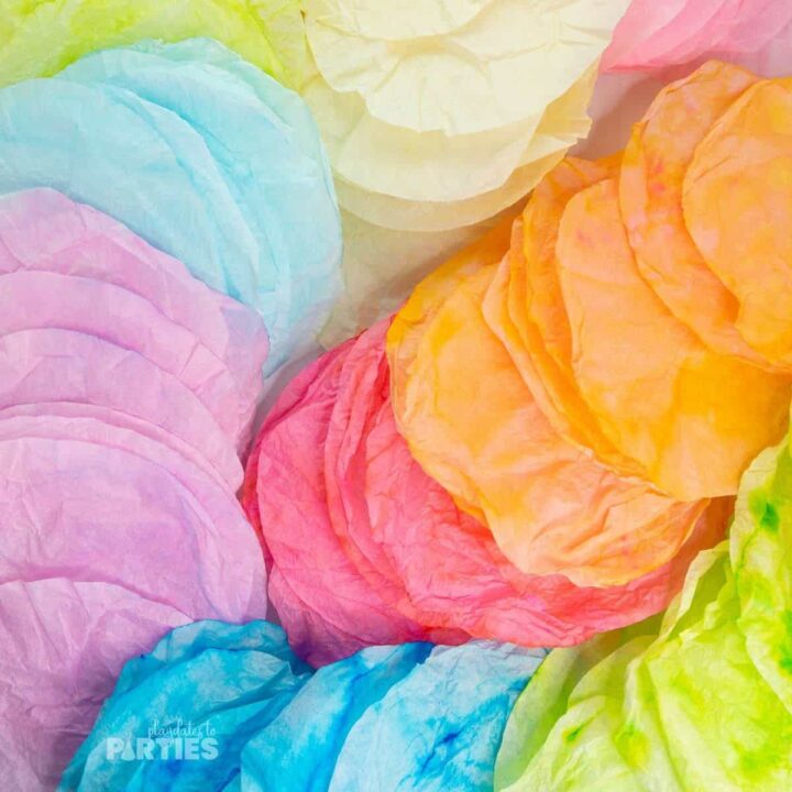 Colorful dyed coffee filters spread out on a flat surface.