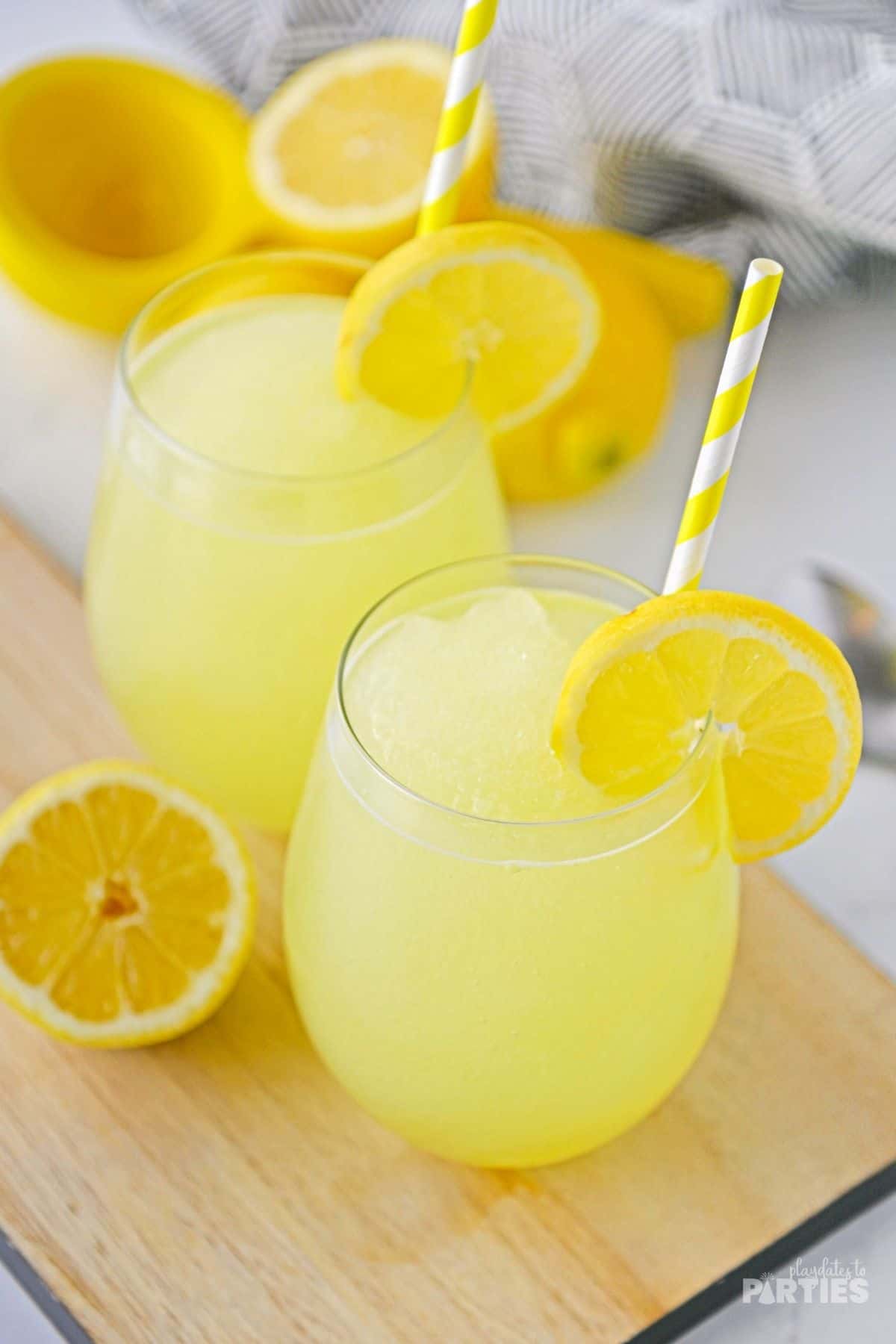 Frozen lemonade in two stemless glasses on a wood board.