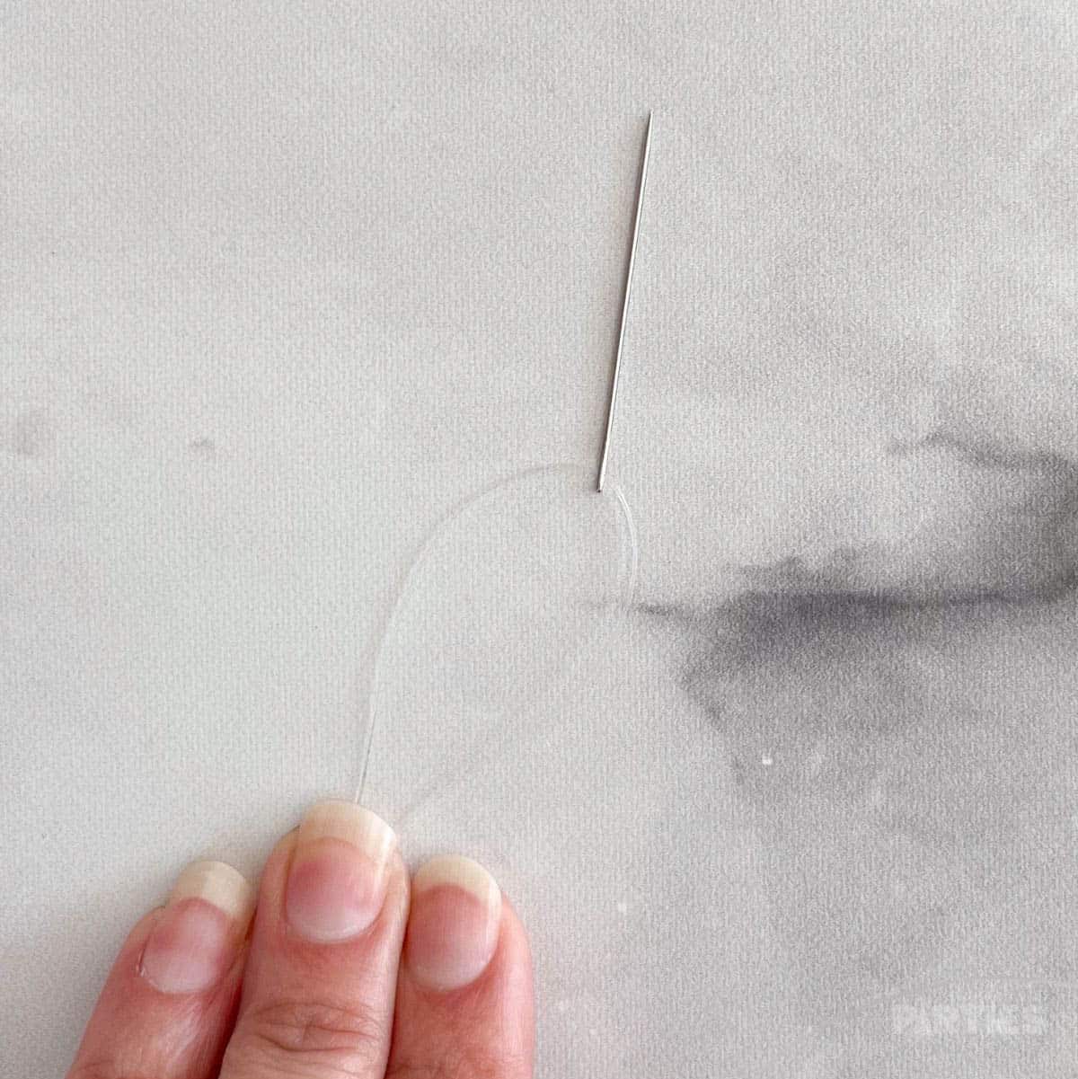 Monofilament threaded through a sewing needle.