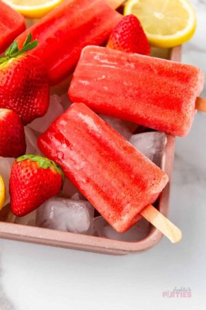 Strawberry lemonade popsicles on a square rose gold pan.