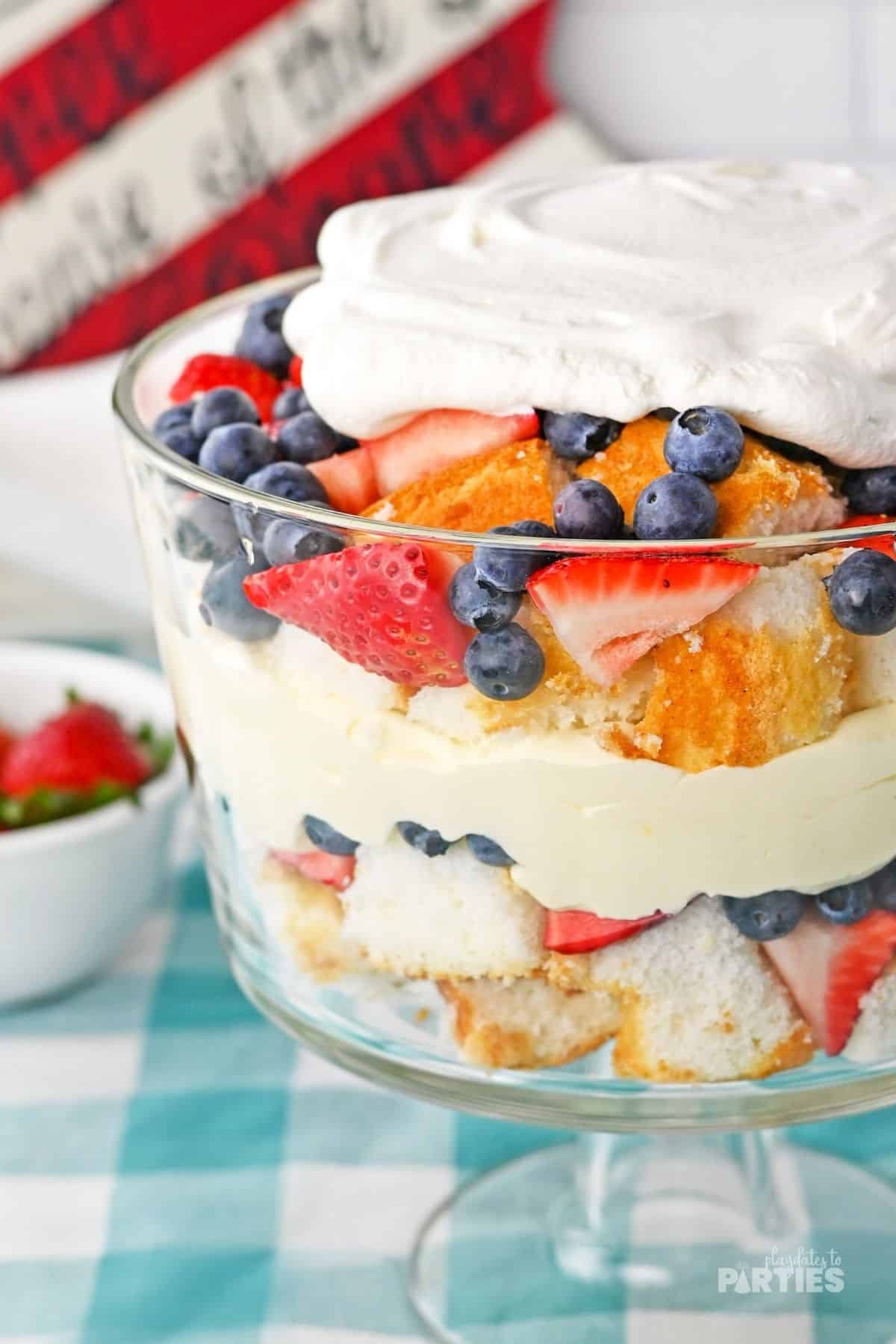 Patriotic layers of berries, pudding, and cake are revealed through the clear trifle bowl.