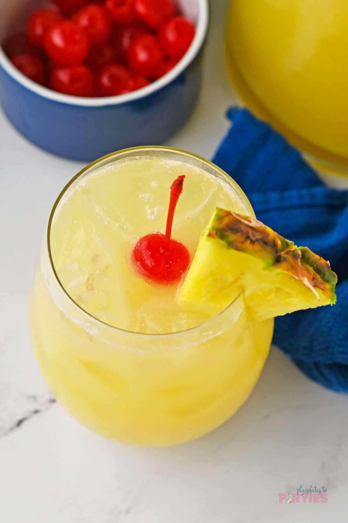A glass filled with pina colada party punch and ice cubes.