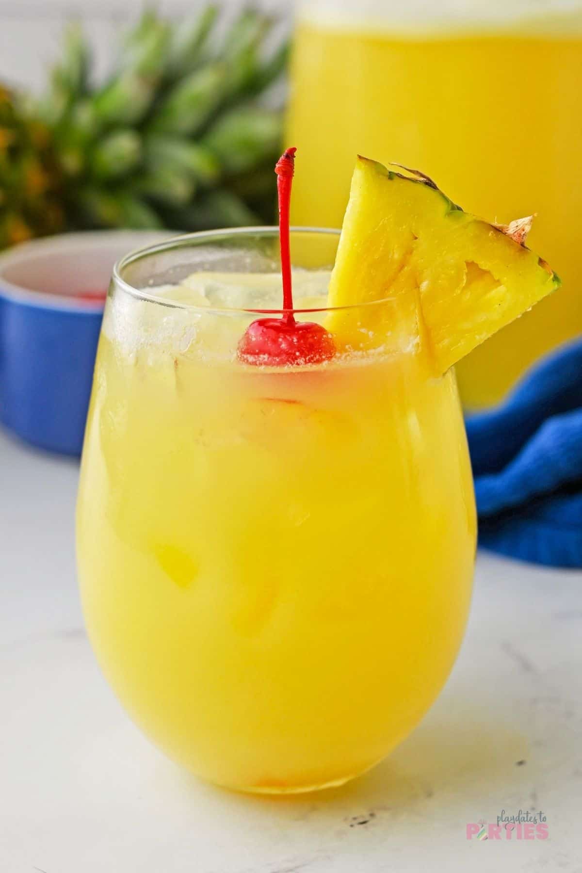 Pineapple coconut juice garnished with maraschino cherries and fresh pineapple.