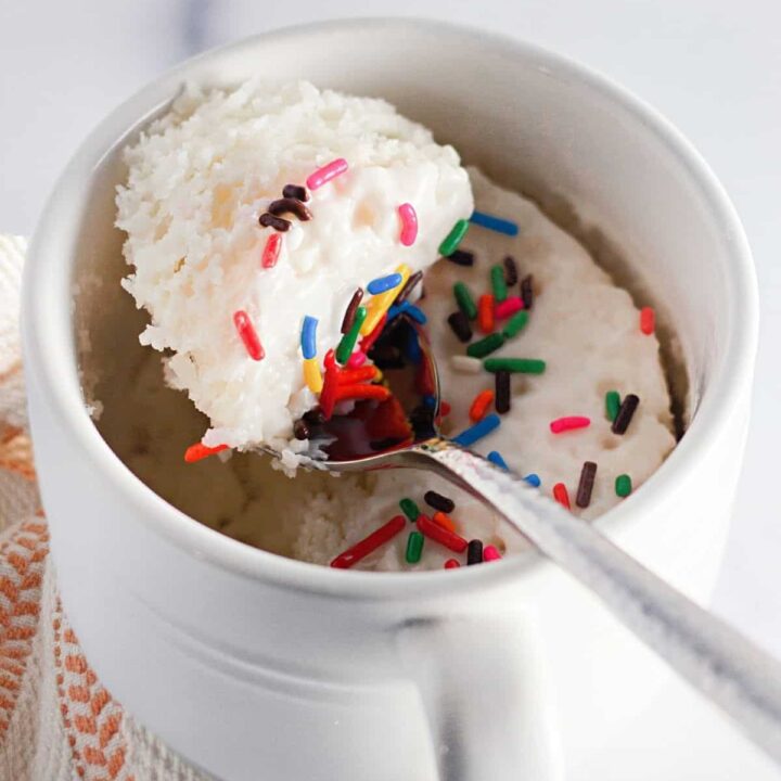 A spoon with cake mix, sprinkles, and frosting.