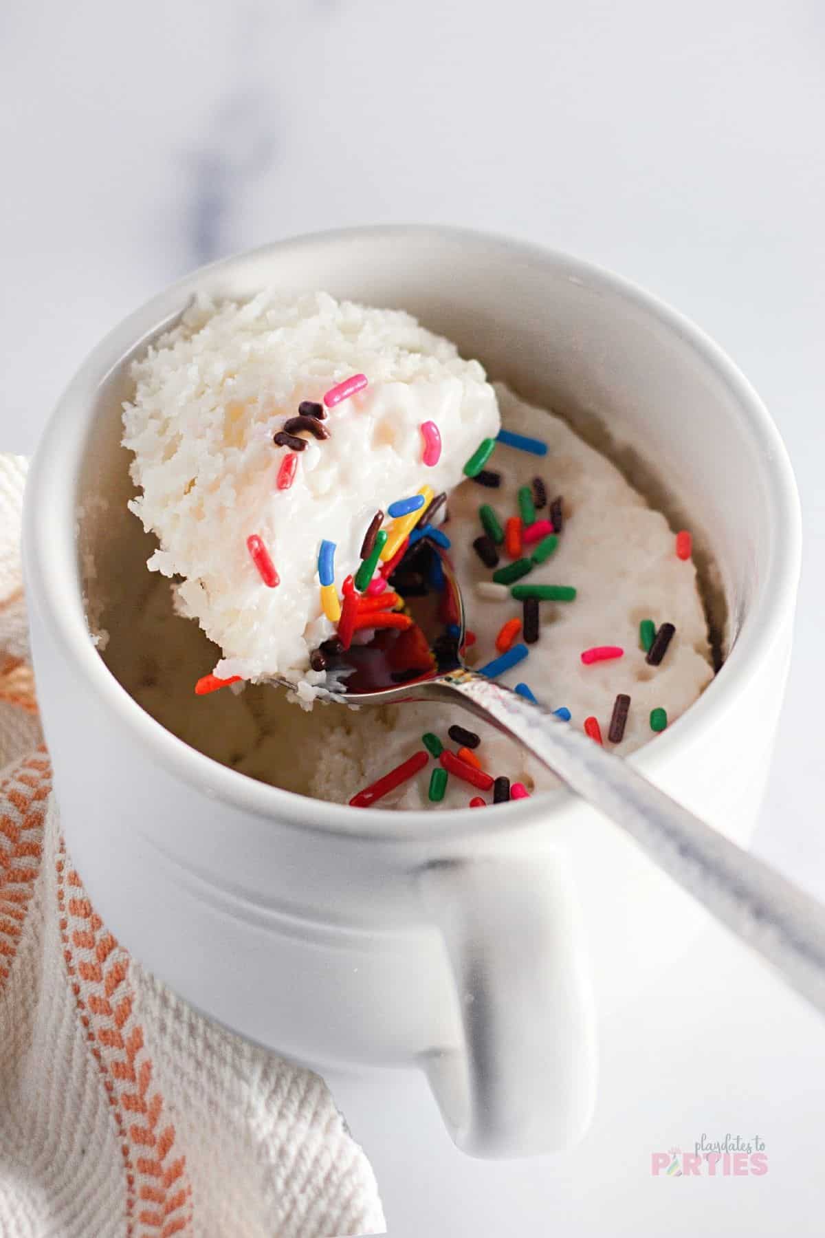 A spoon with cake mix, sprinkles, and frosting.