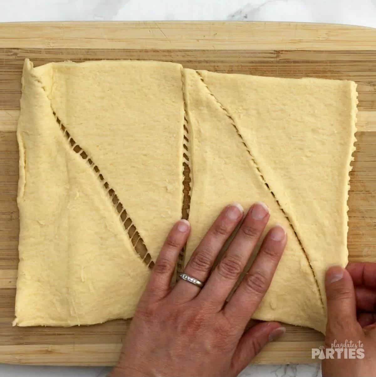 Crescent roll dough rolled out onto a cutting board.