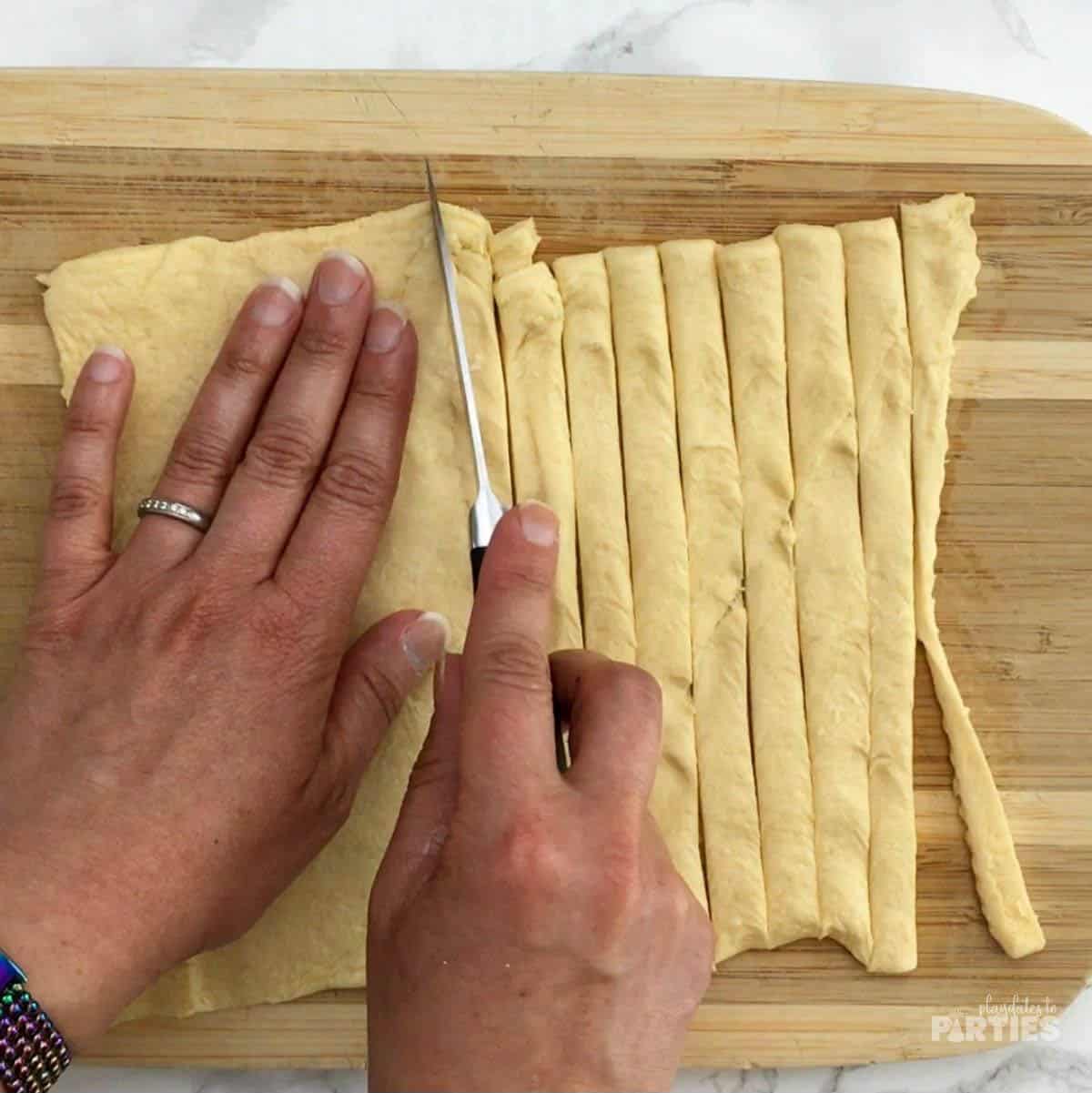 Cutting strips of dough with a paring knife.