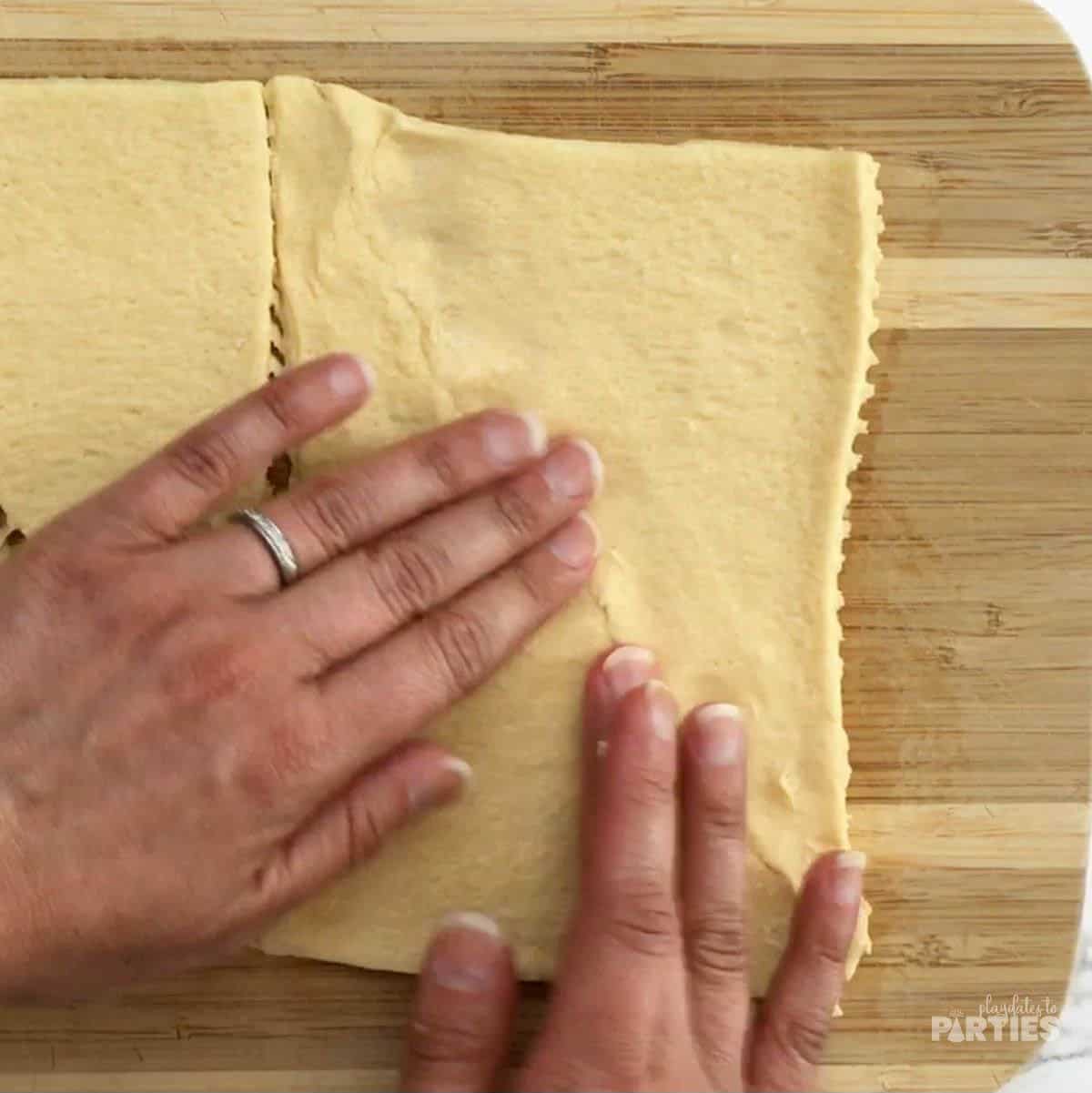Pinching together crescent roll dough so it stays together.