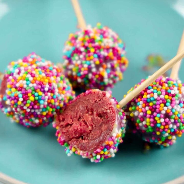 A cake pop is cut in half to show the red velvet interior.