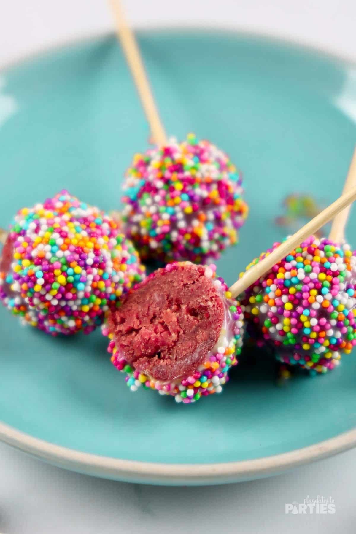 A cake pop is cut in half to show the red velvet interior.