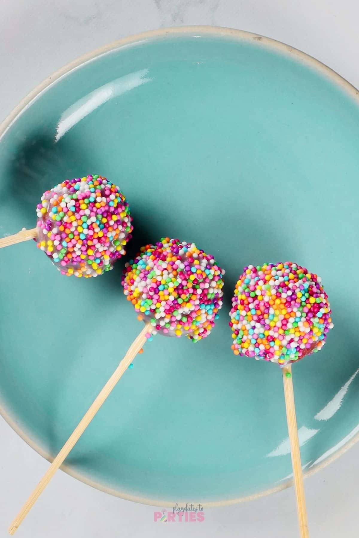Sprinkle covered cake pops on a blue plate ready for a party.