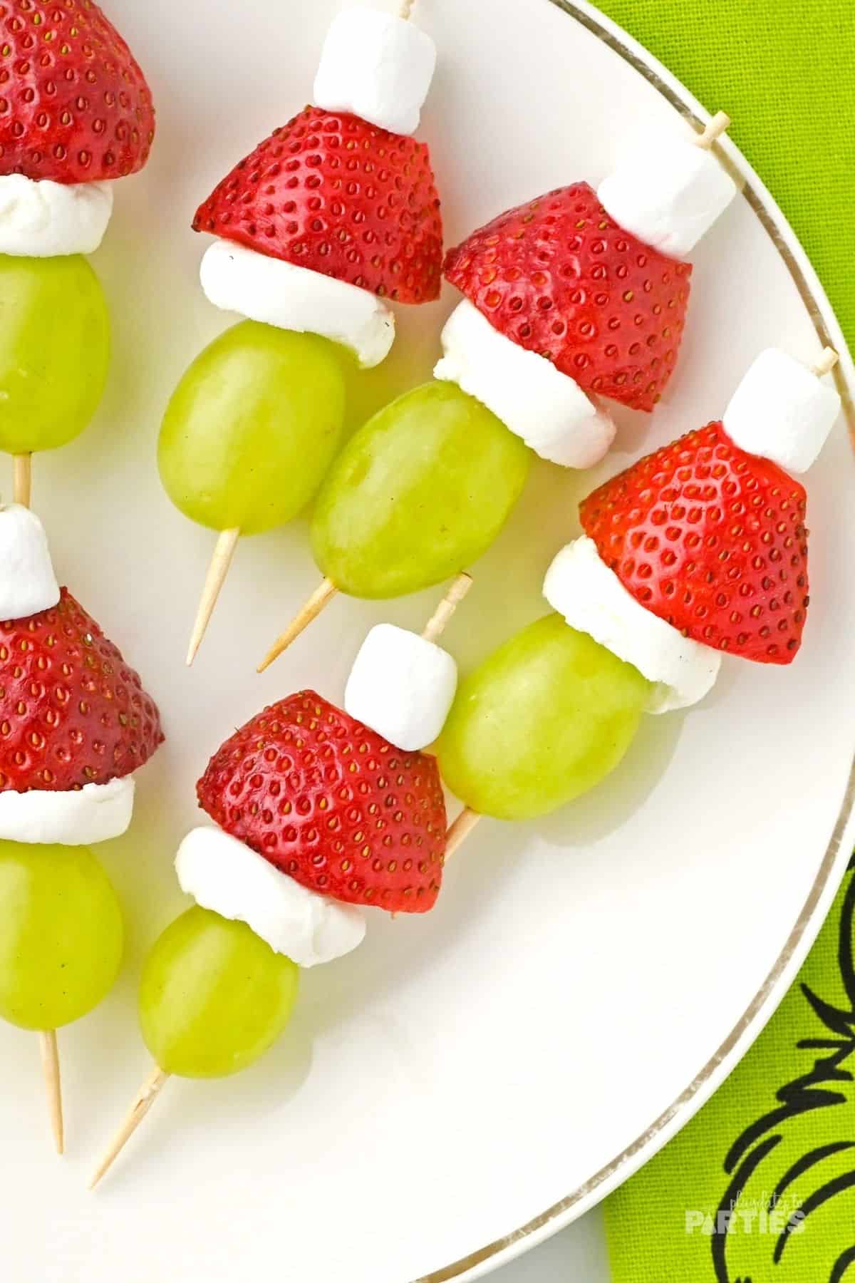 Grape and strawberry fruit skewers on a white plate for a Christmas party.