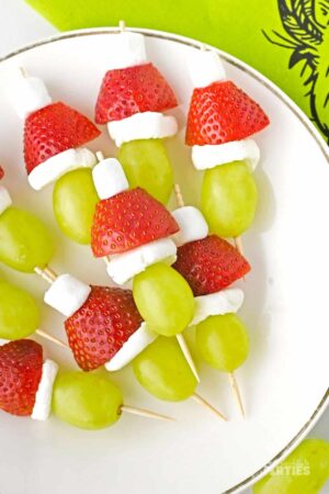 Grinch Fruit kabobs on a white plate.