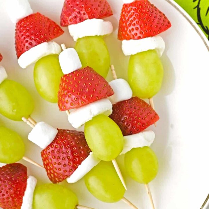 Grinch Fruit kabobs on a white plate.