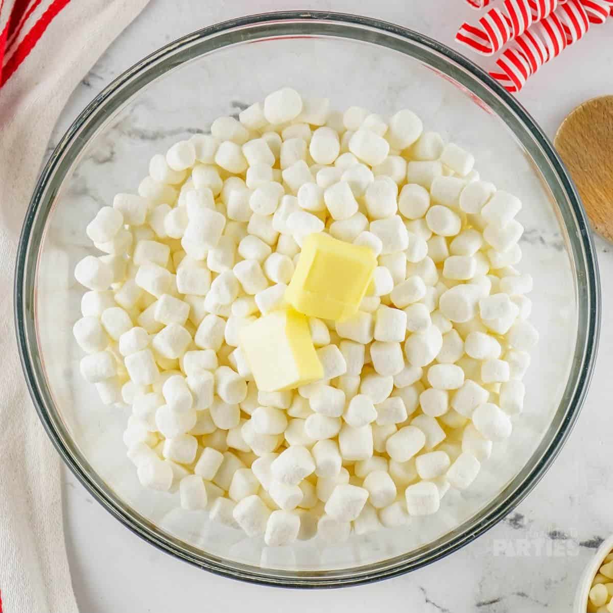Mini marshmallows and butter cubes in a glass bowl.