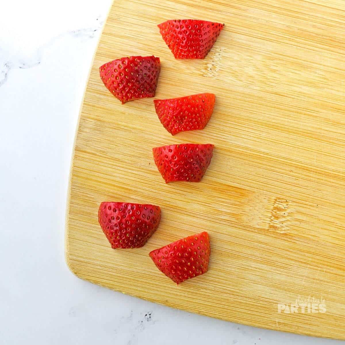 Strawberries cut up on a cutting board.