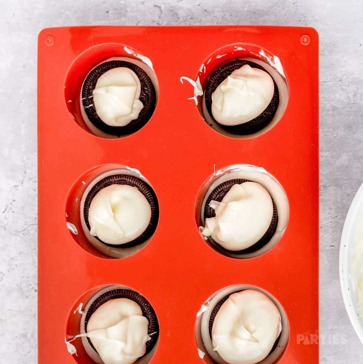 White chocolate is dolloped on top of Oreo cookies.