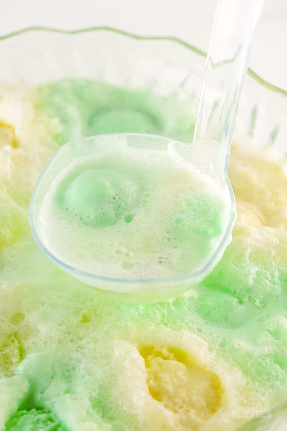 A ladle of party punch with green sherbet.