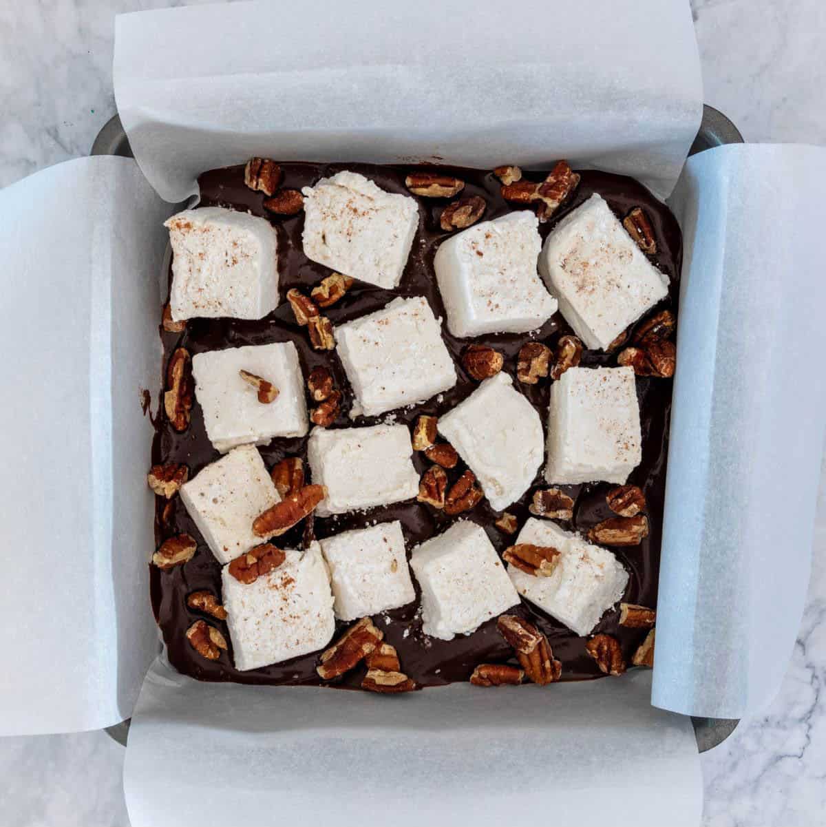 Marshmallows and pecans on a layer of chocolate.