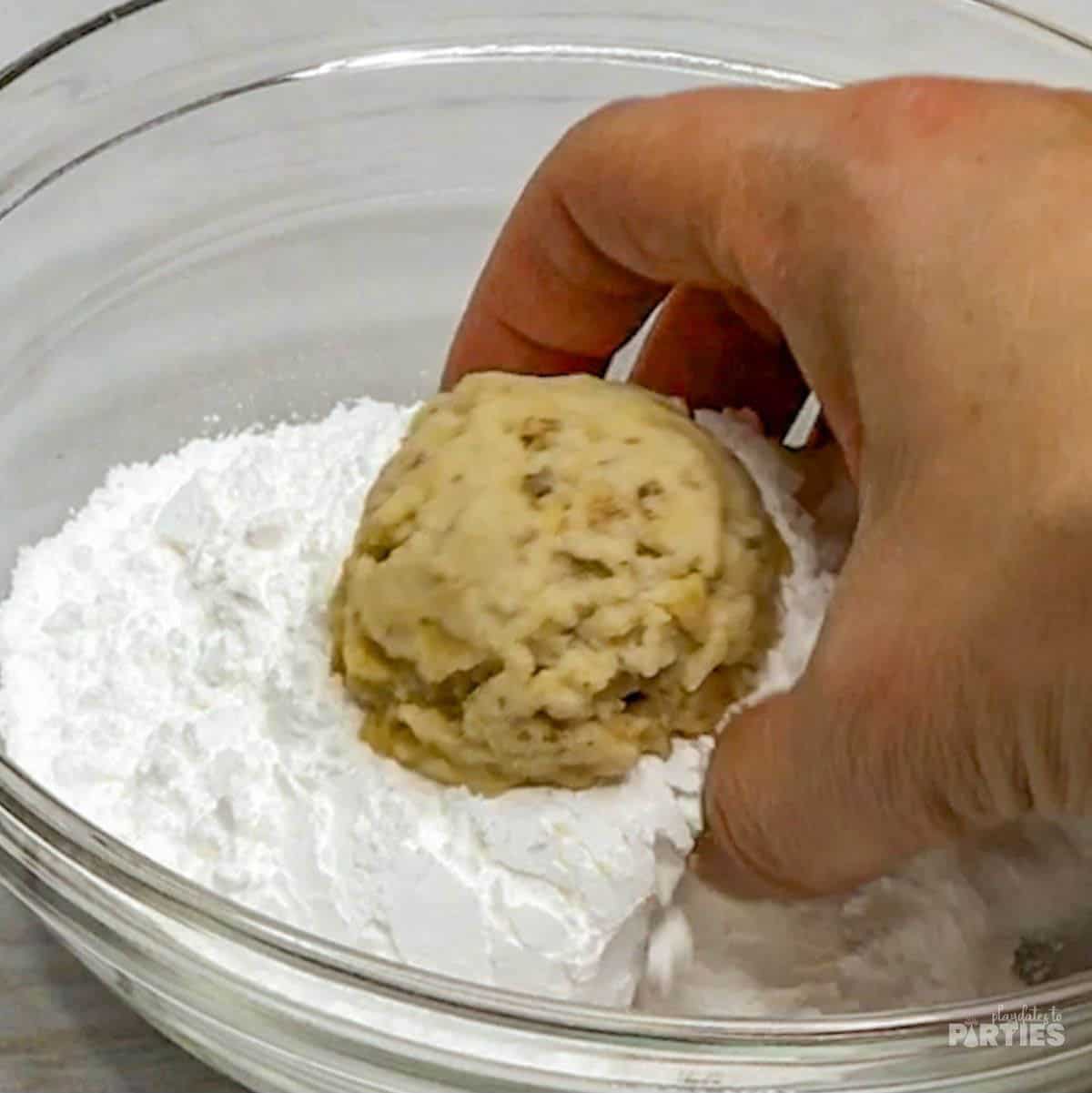 Rolling warm cookies in powdered sugar.