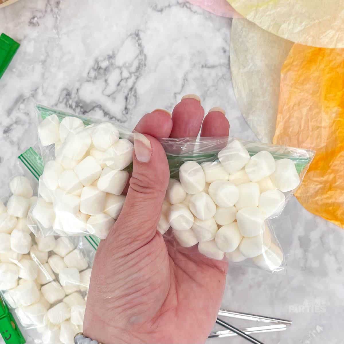 A woman's hand is dividing a bag of marshmallows.