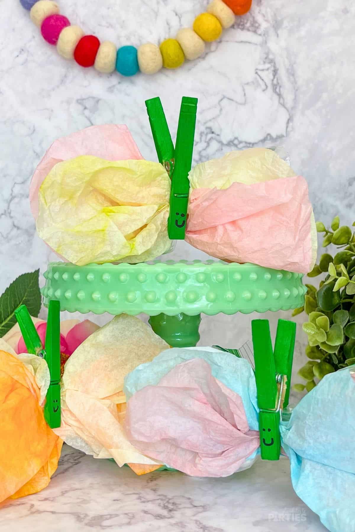 Butterfly Party favors with coffee filters sit on a green cake stand.