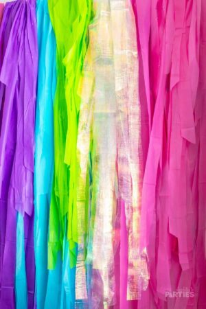 DIY Fringe Party Backdrop in purple, blue, green, and pink.
