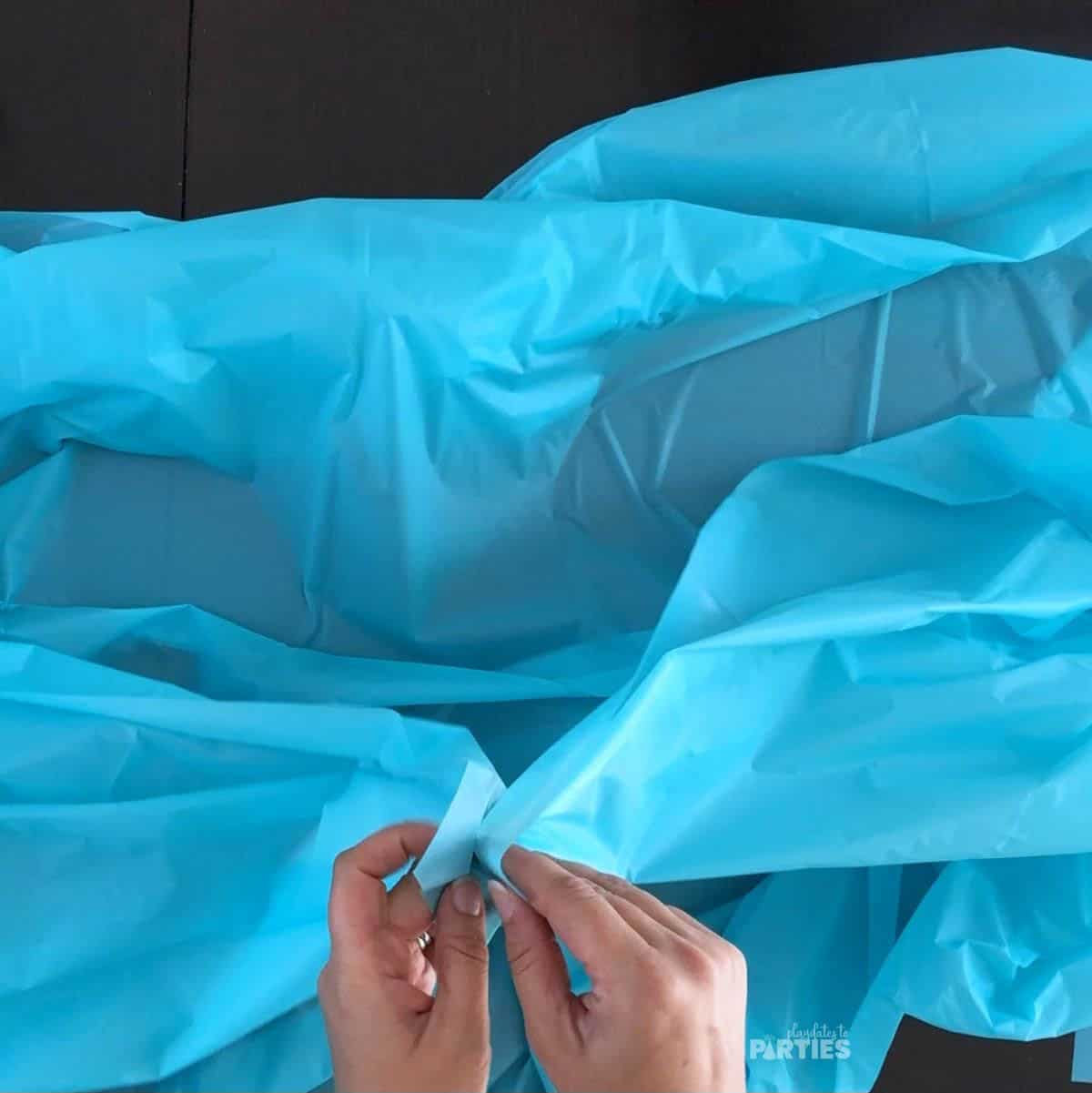 Folding the outside corners of the plastic tablecloth.