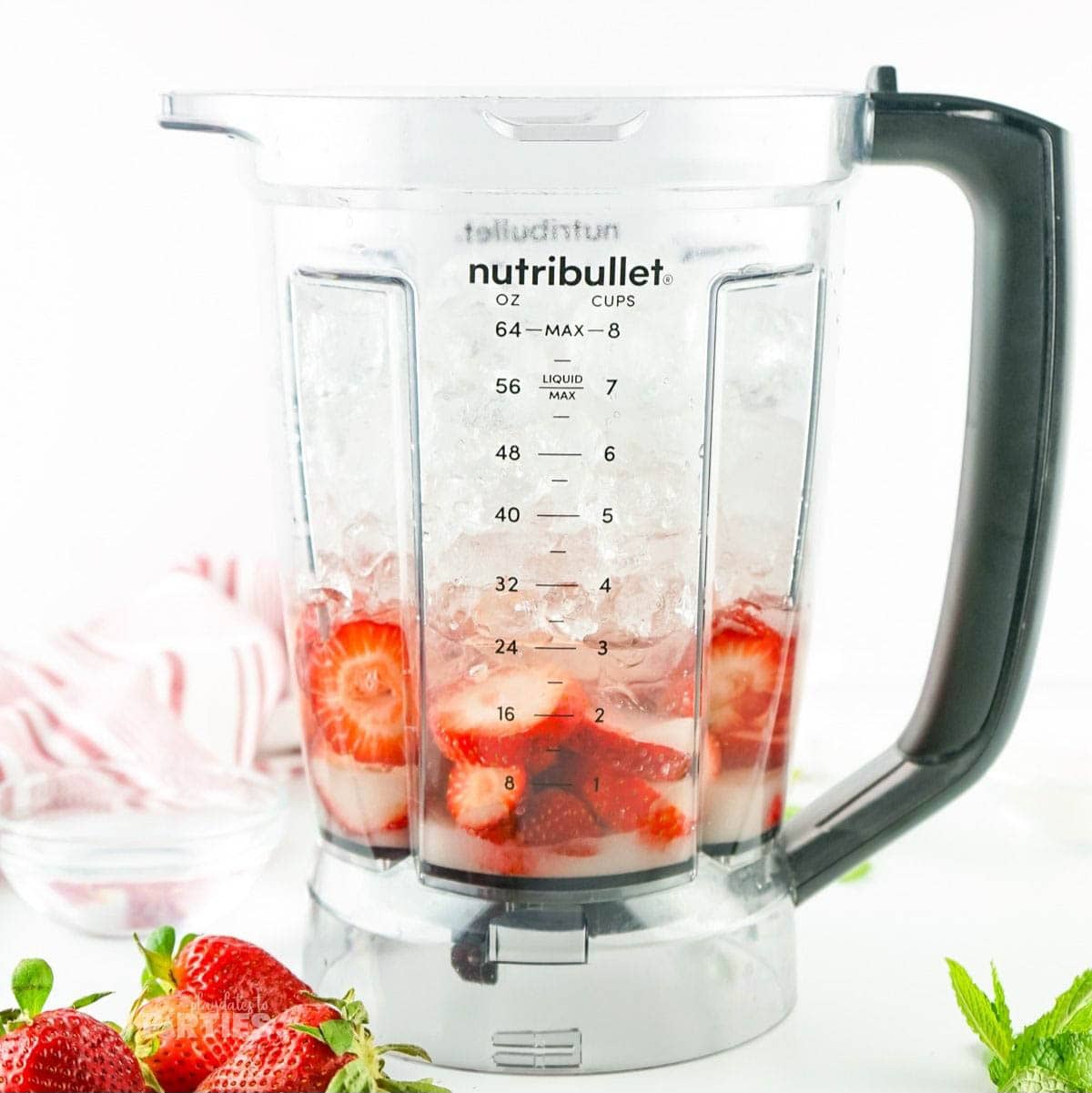 Strawberries, ice, water, and sugar in a blender cup.