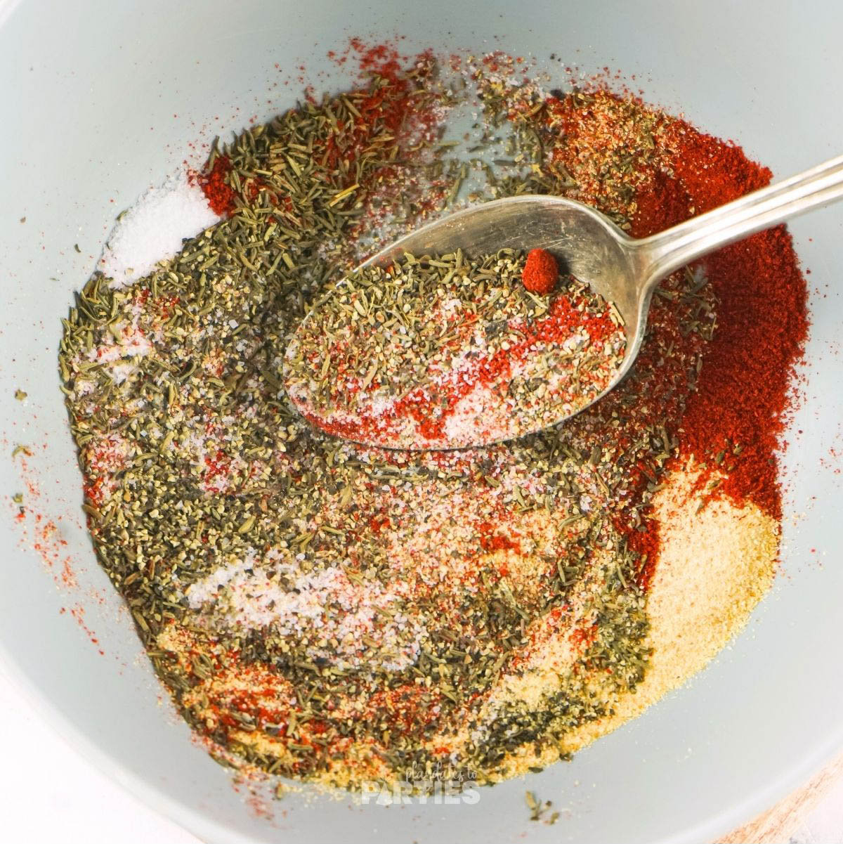 A bowl of seasonings getting mixed together with a spoon.