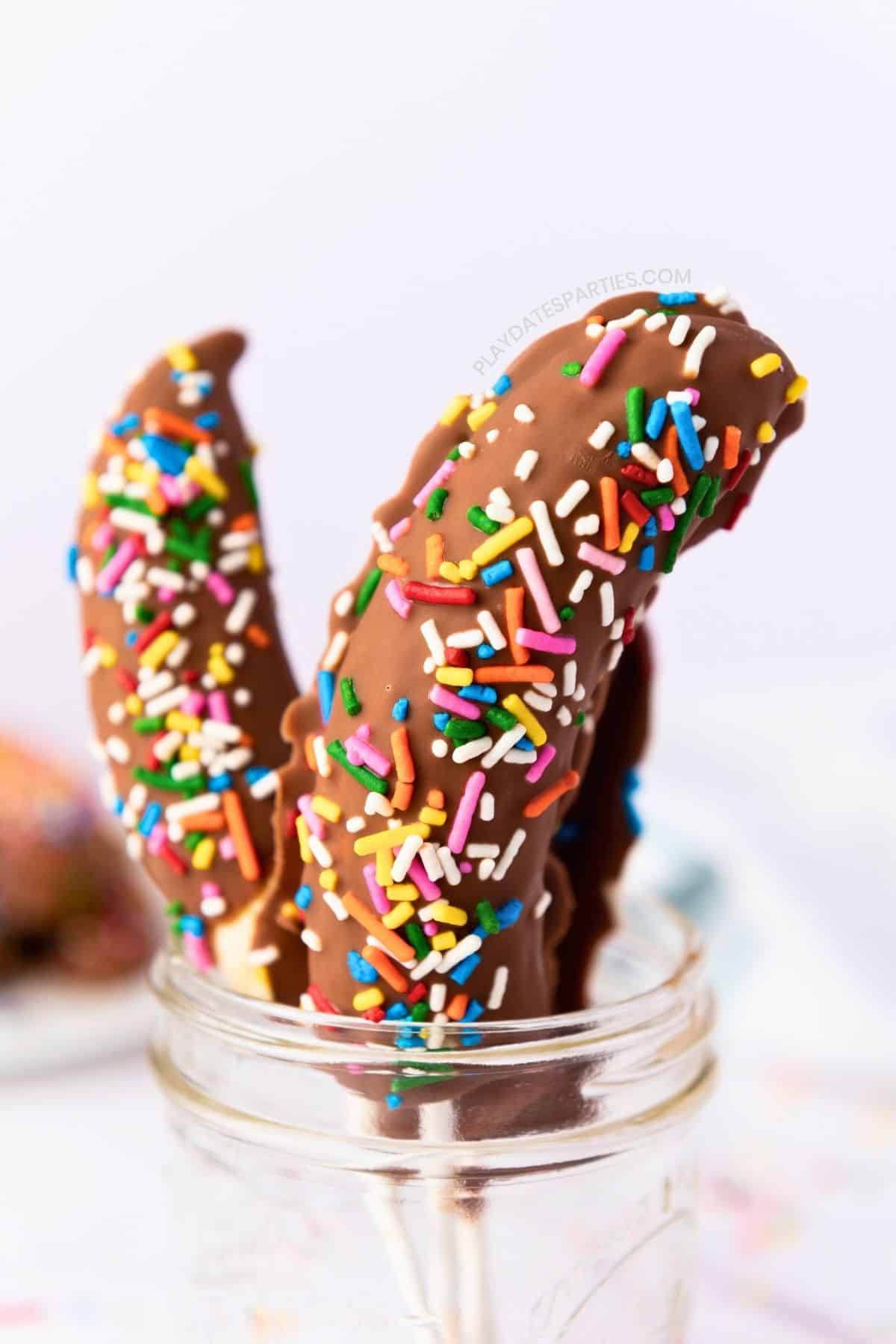 Chocolate covered banana pops displayed in a glass jar.