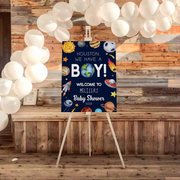 Houston we have a boy baby shower sign on an easel in front of a balloon garland.