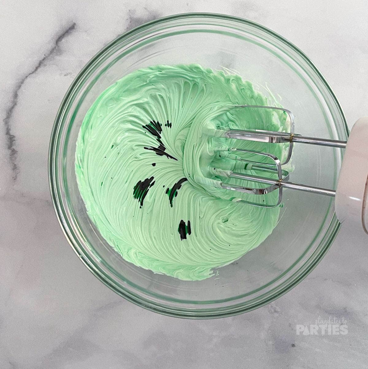 Dying frosting with green food coloring.